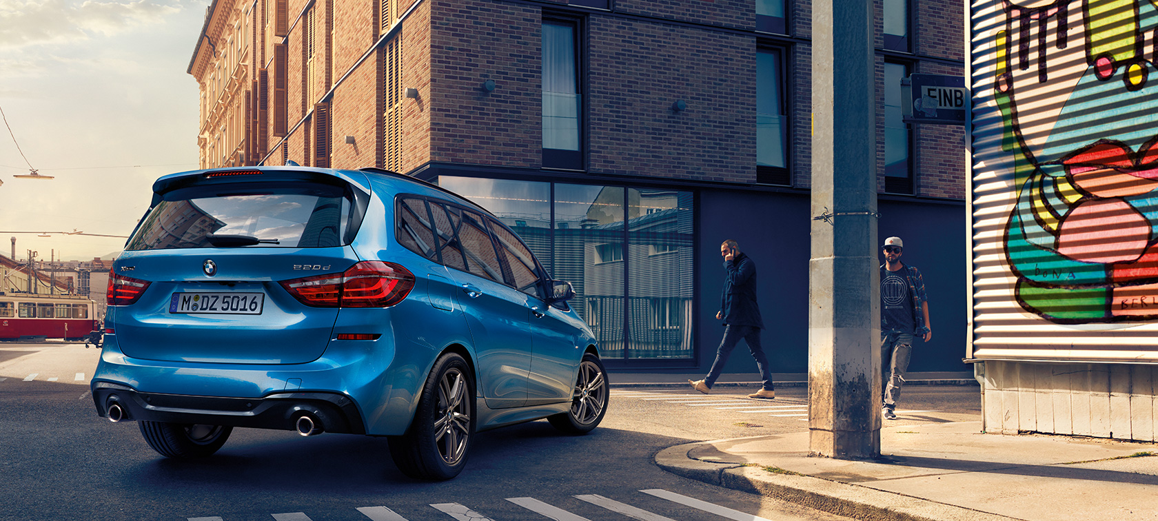 Man next to BMW 2 Series Gran Tourer F46 2018 Misano Blue metallic bird’s-eye view parking on the street