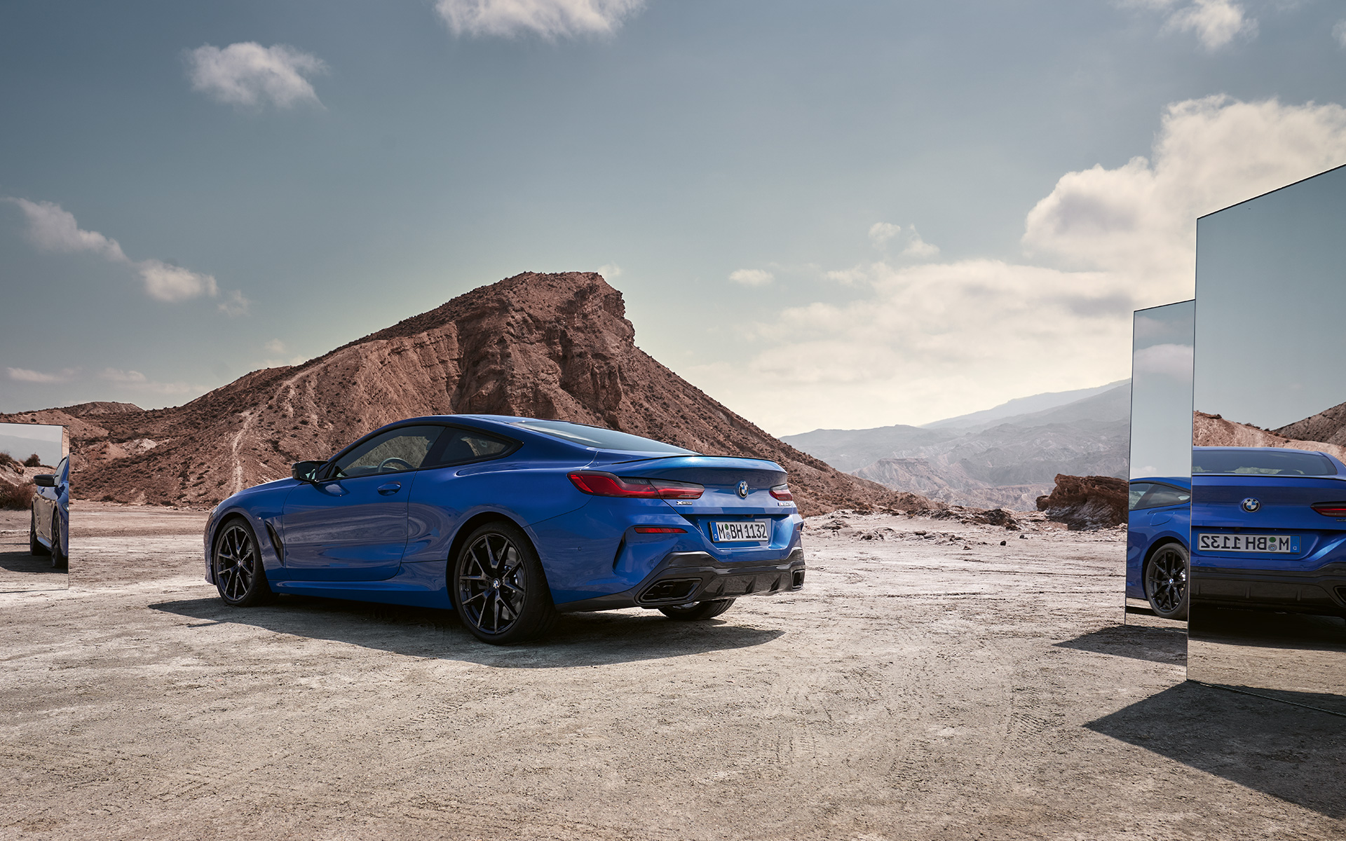 The BMW M850i xDrive Coupé G15 LCI Facelift 2022 M Portimao Blue metallic rear view standing with mirrors